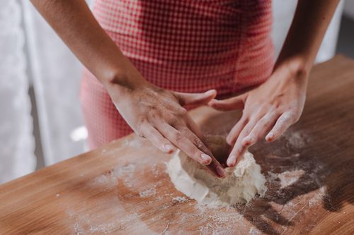 Free Close-up of woman shaping fresh pasta dough on a wooden surface. Stock Photo