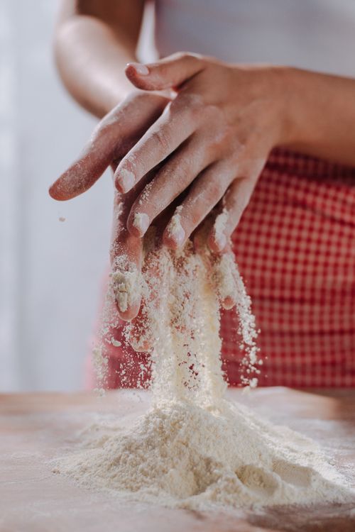 Free Close-up of hands mixing flour on a wooden surface for pasta making. Stock Photo