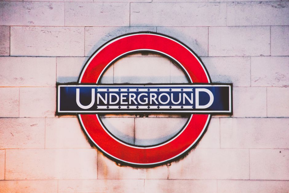 Vibrant shot of the London Underground sign against a textured wall, highlighting urban transport.