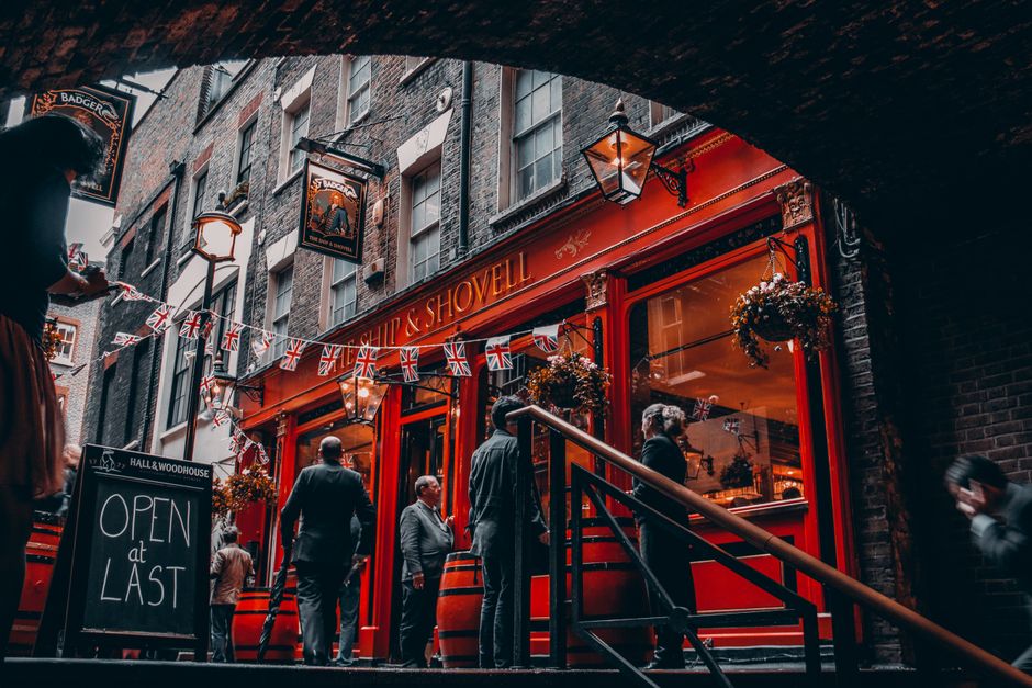 Vibrant London pub with Union Jack flags and people socializing outside.