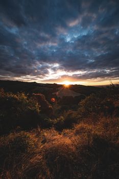 Scenic view of a golden sunset over a mountainous landscape with dramatic clouds.