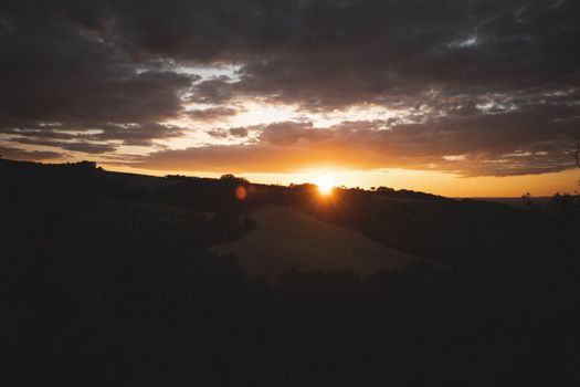 Stunning sunset view highlighting landscape and vibrant sky colors over rolling hills.