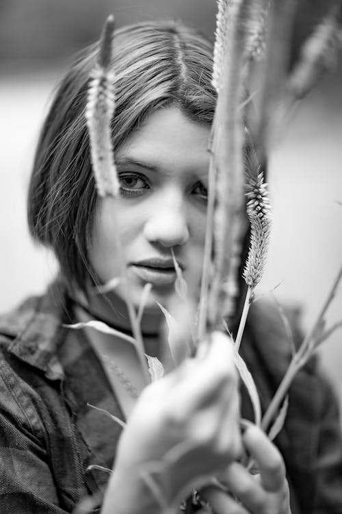 Grayscale Photo of a Woman Holding Flowers