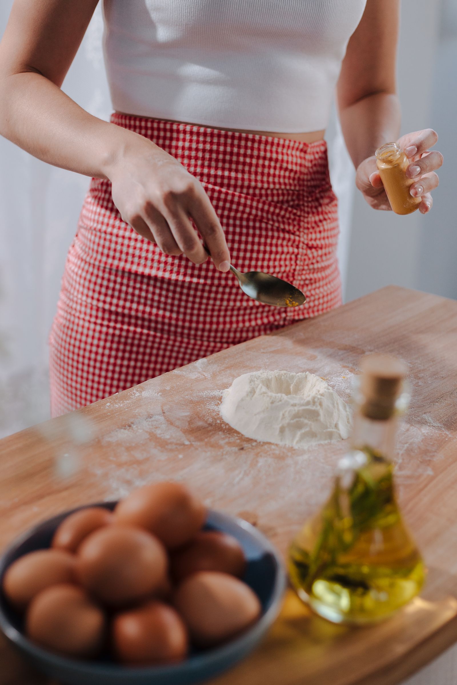 Cook working with eggs, flour, and olive oil while preparing pasta.