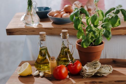 Free Fresh Italian cooking ingredients including olive oil, tomatoes, and basil on wooden tables. Stock Photo