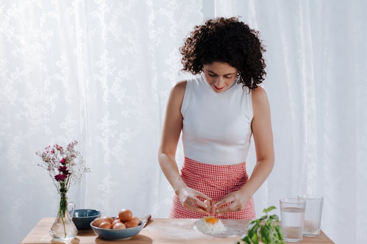 Woman Breaking Eggs Into Flour Mound