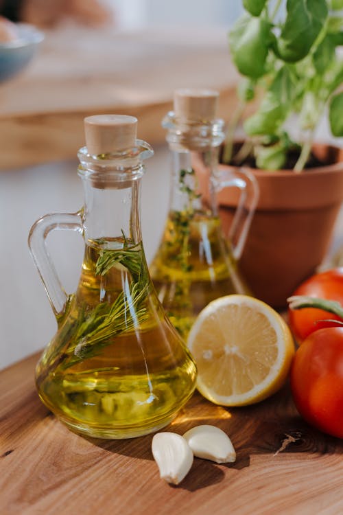 Free Bottles of olive oil with herbs, tomatoes, and lemon for Mediterranean cuisine. Stock Photo