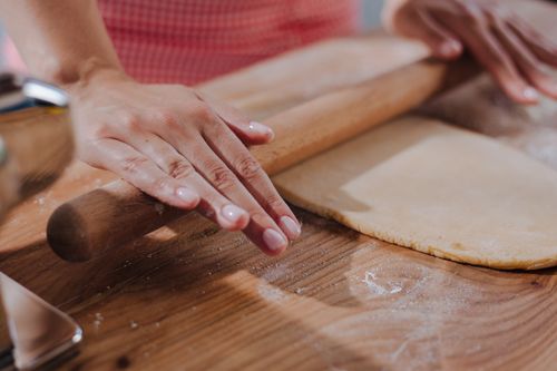 Free Close-up of hands rolling dough on a wooden surface, capturing the art of homemade pasta making. Stock Photo