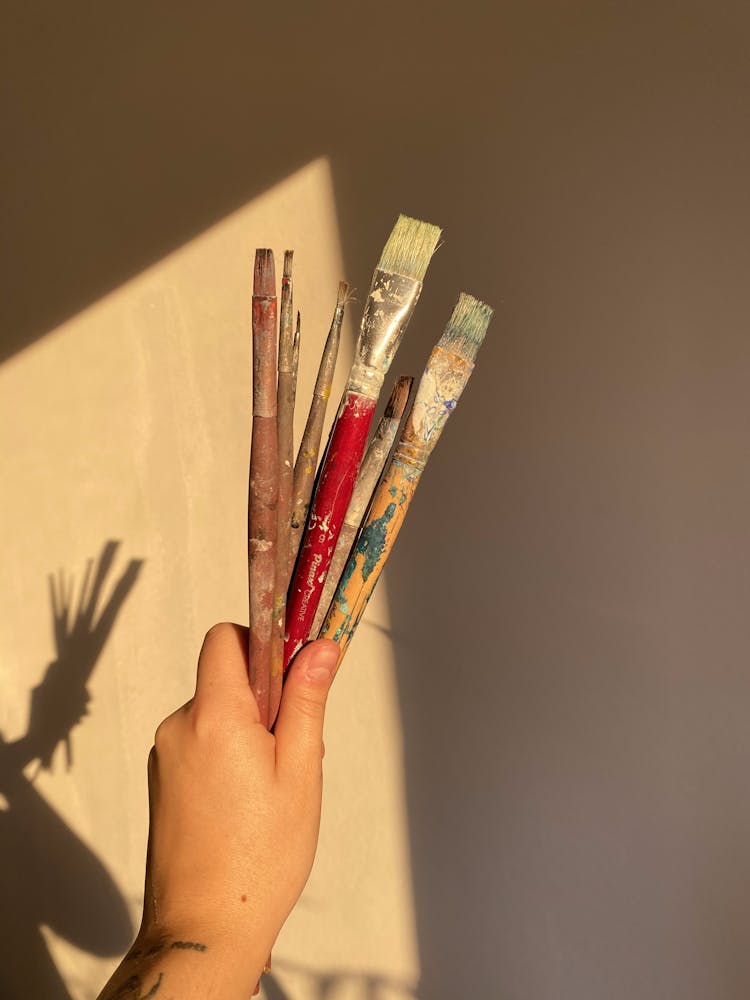 A Person Holding Used Paintbrushes