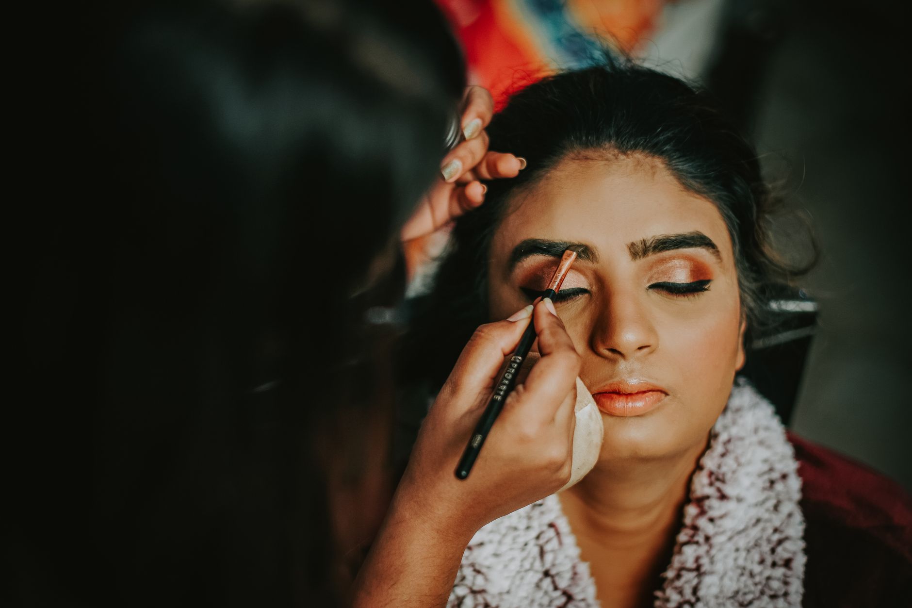 Close-up of a woman getting her makeup done, highlighting beauty and precision.