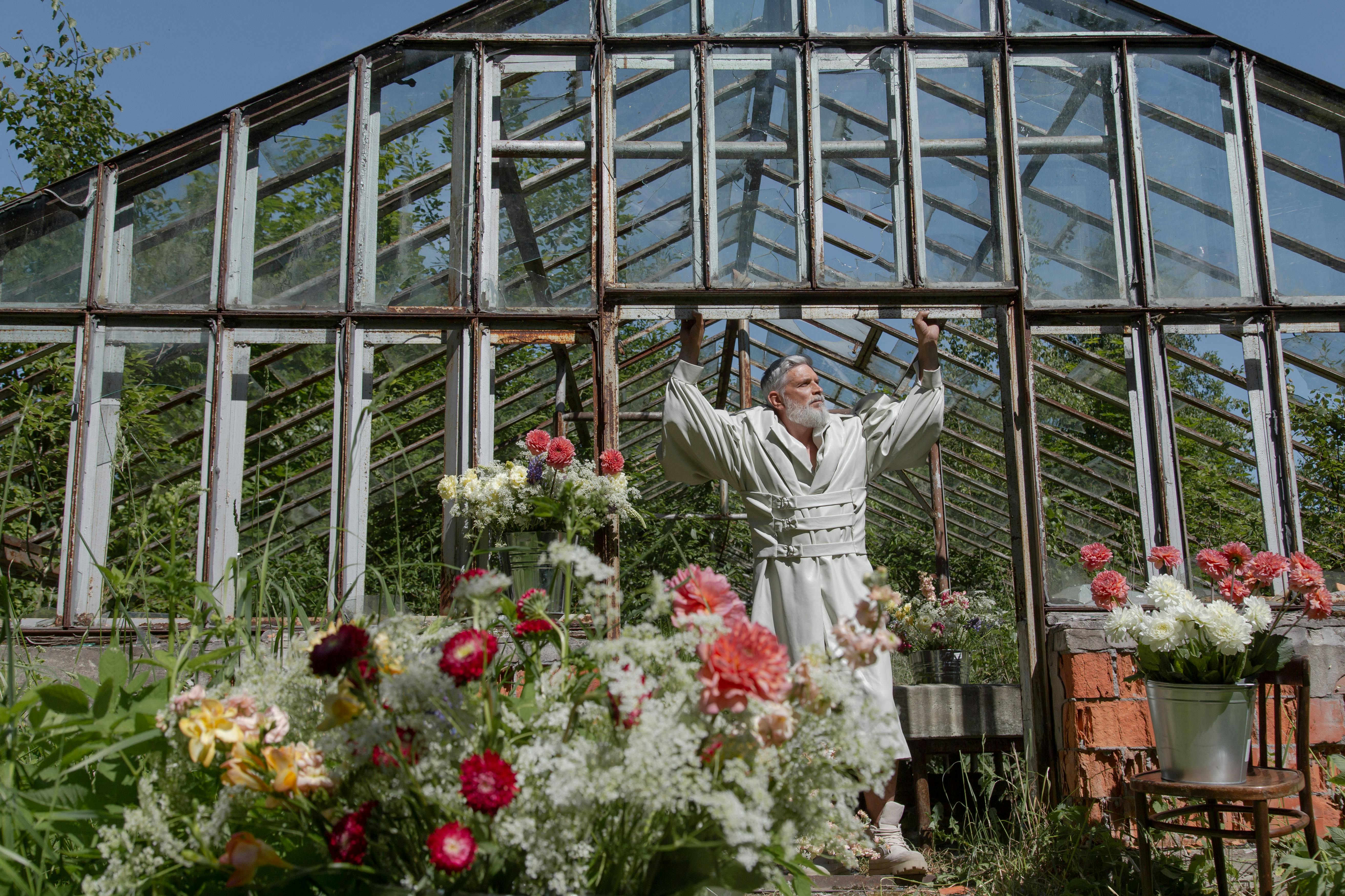 a man standing on the doorway of a greenhouse