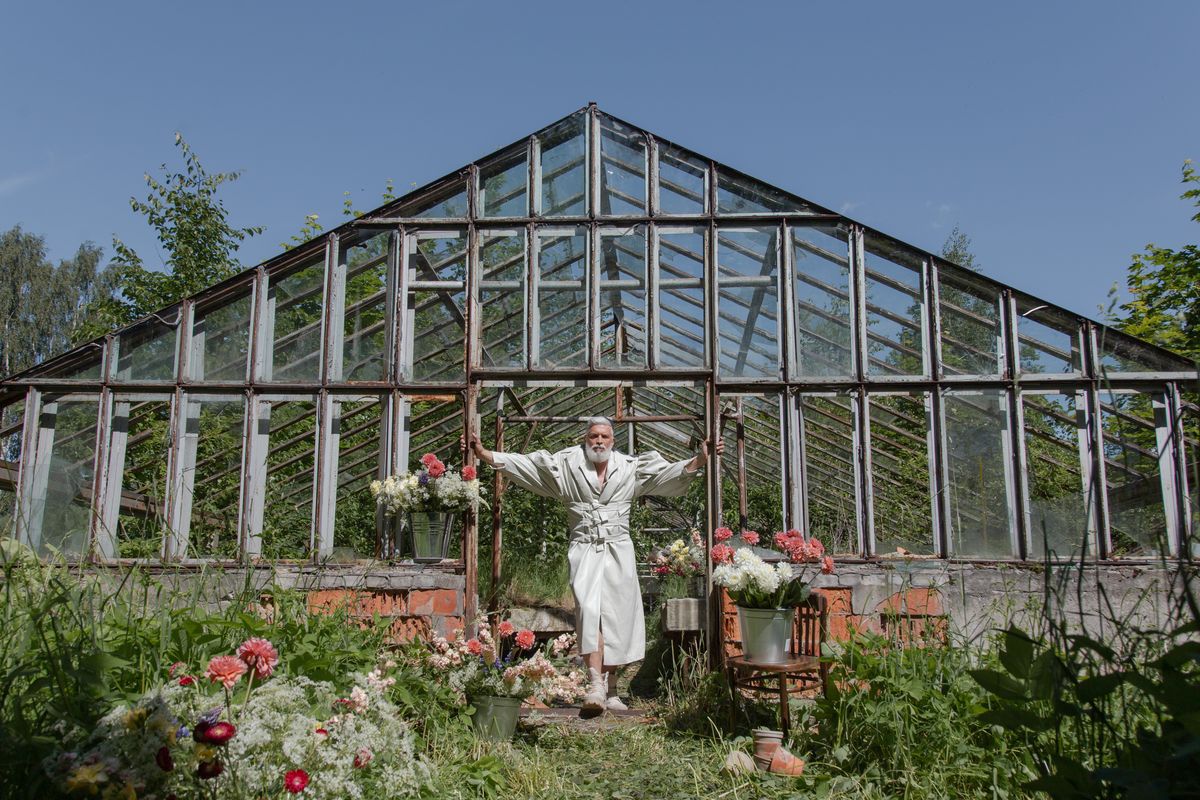 Senior man standing in a greenhouse surrounded by flowers