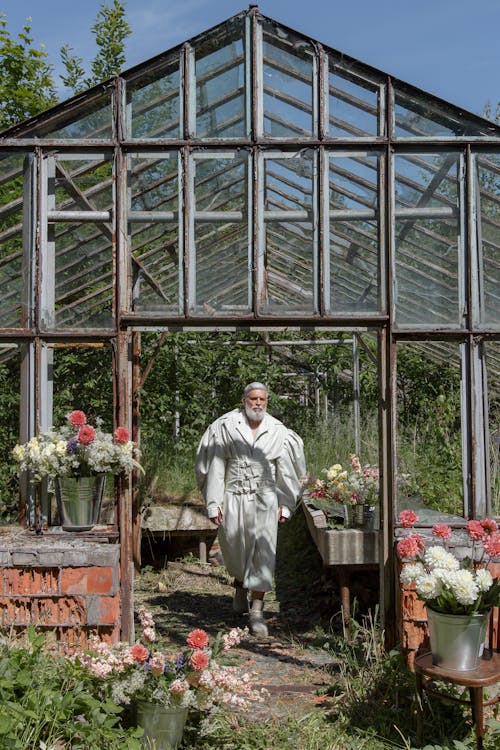 Free Photograph of a Man in a Coat Walking in an Abandoned Greenhouse Stock Photo
