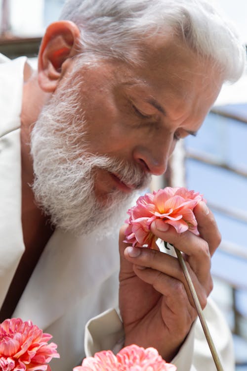 Photo of an Elderly Man Smelling a Dahlia Flower