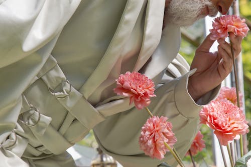 Photograph of an Elderly Person Smelling Pink Dahlia Flowers
