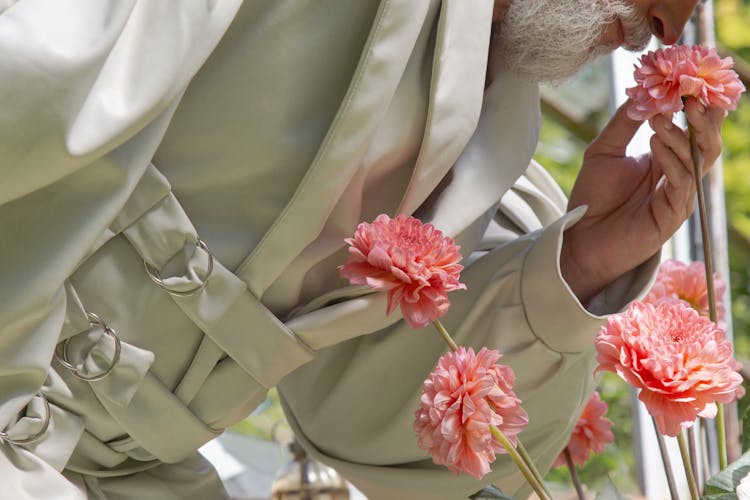 Photograph Of An Elderly Person Smelling Pink Dahlia Flowers