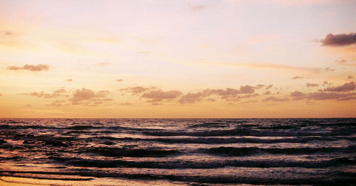 Serene view of the Tel Aviv beach at sunset, showcasing the calming waves and vibrant sky.