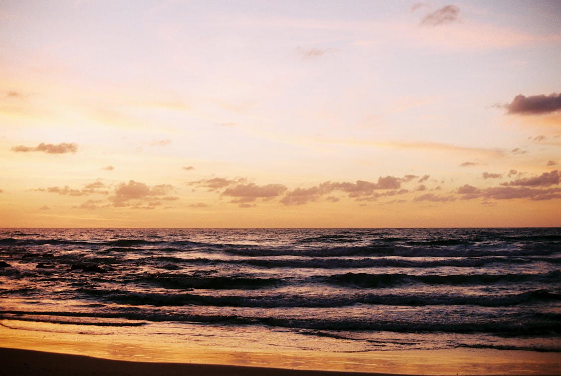 Photograph of Sea Waves Crashing on Shore during Sunset