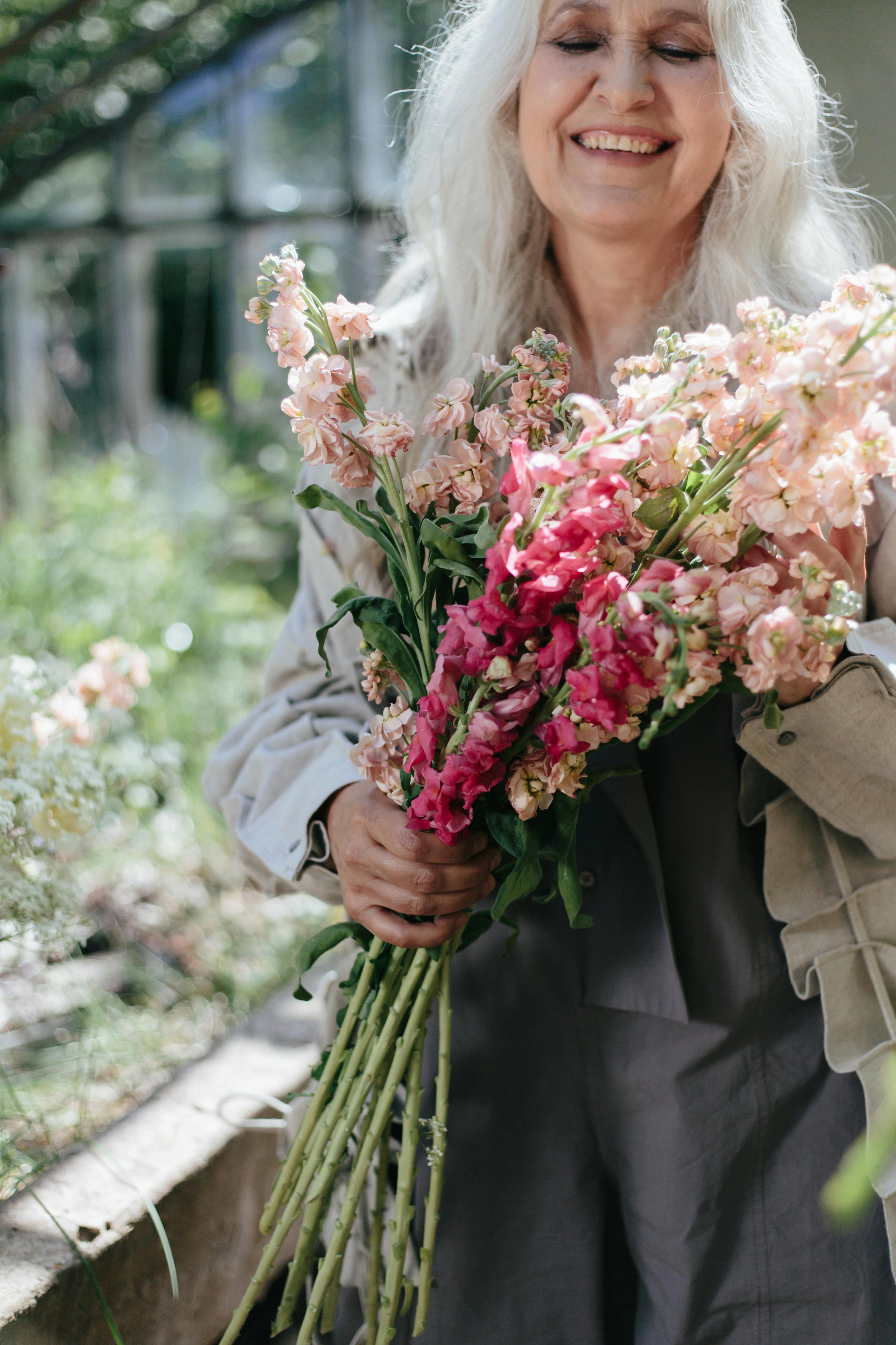 woman in gray jacket holding pink flowers