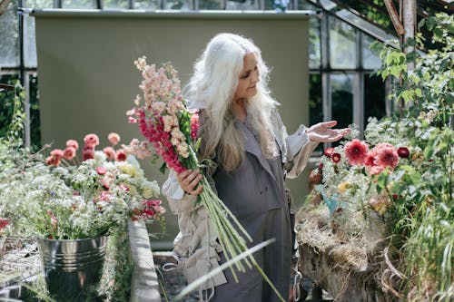 Photograph of a Woman with Gray Hair Holding Different Kinds of Flowers