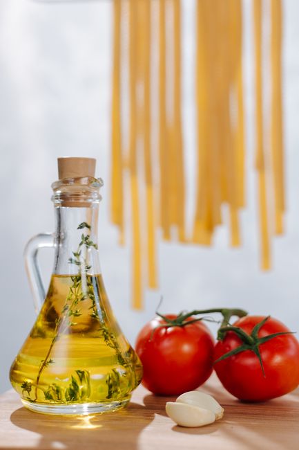 Aromatic Italian ingredients with drying pasta, olive oil, tomatoes, and garlic on a wooden surface.