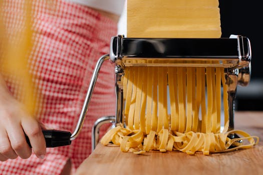 Homemade pasta being made with a machine. Close-up captures fresh noodles.