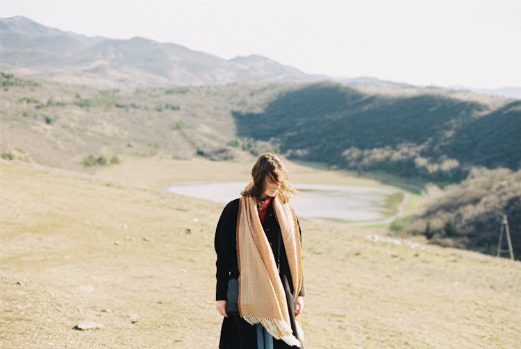 Woman In Coat On Plains With Lake Behind