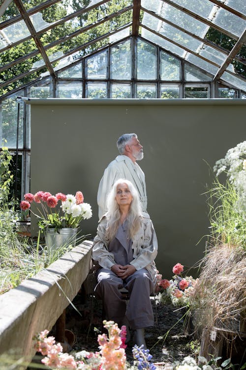 Elderly Man and Woman Sitting in a Greenhouse with Flowers