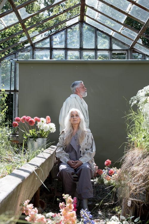 Free Elderly couple in a greenhouse surrounded by vibrant flowers. Bright, serene atmosphere. Stock Photo