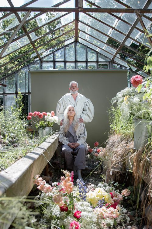 Free A senior couple surrounded by colorful flowers inside a rustic greenhouse. Stock Photo