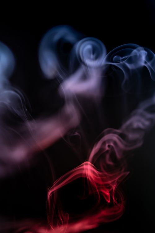 Free Abstract image of blue and red smoke swirls on a black background, capturing motion and glow. Stock Photo