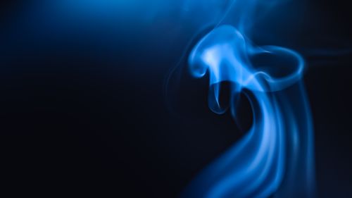 Free Abstract image of blue smoke swirling on a dark background, creating a mystical atmosphere. Stock Photo