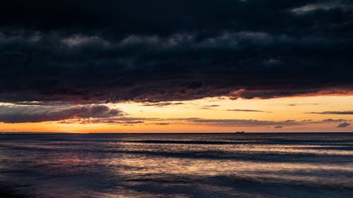 Body of Water Under Dark Cloudy Sky during Sunset