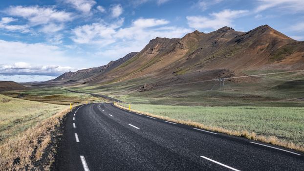 Breathtaking view of an empty road winding through Icelandic mountains and countryside.
