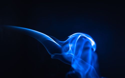 Free Dynamic blue smoke illuminated against a dark background, creating an ethereal abstract effect. Stock Photo