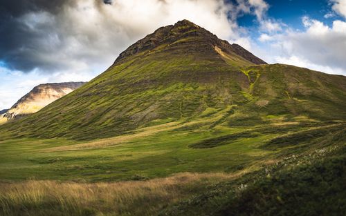 Free Breathtaking view of a lush green mountain and cloudy sky in Iceland's scenic landscape. Stock Photo