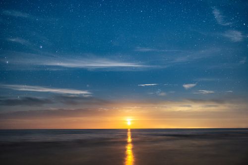Free Stunning night sky view over a calm seaside at Jantar, Poland, with stars and moonrise reflection. Stock Photo