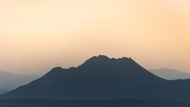Silhouette of an Icelandic hill against a warm twilight sky, showcasing natural beauty.