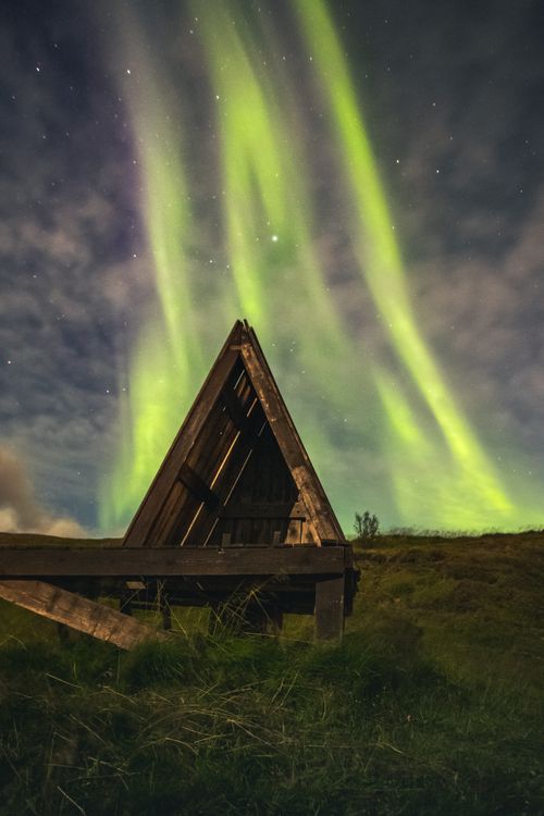 Free Stunning display of the Northern Lights over a wooden hut in Akureyri, Iceland. Stock Photo