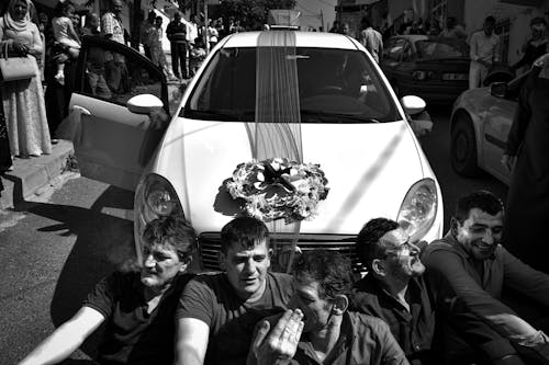 Monochrome Photograph of Men Sitting in Front of a Car