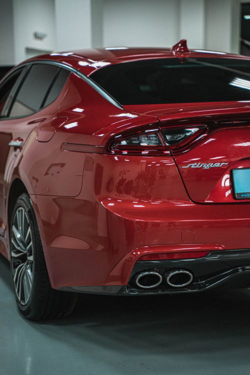 Free Stylish red sports car captured indoors showcasing a modern taillight and exhaust design. Stock Photo