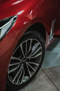 Close-up view of a red Kia car showcasing its elegant wheel design in an indoor setting.