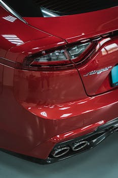 A detailed view of a red car's taillight and exhaust captured in an indoor setting.