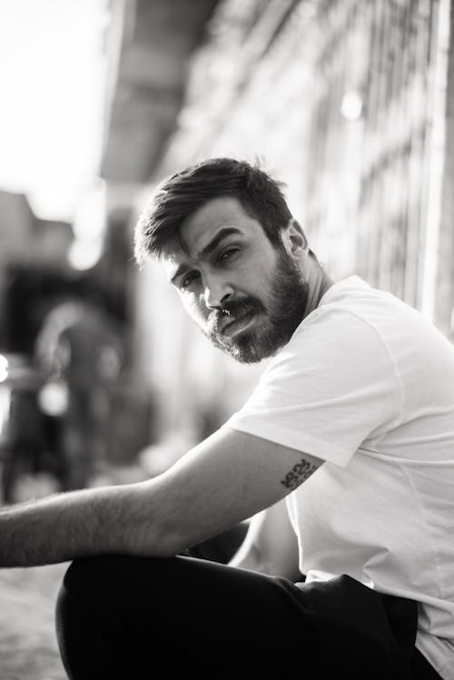 Man Wearing a White shirt Sitting Against the Wall