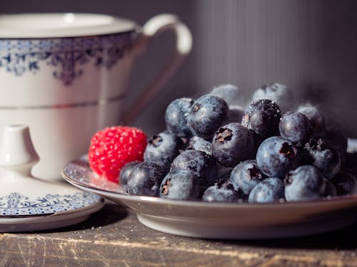 Blueberries and a Raspberry on a Porcelain Plate