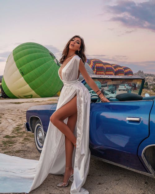 Woman in a White Dress Posing on a Blue Car