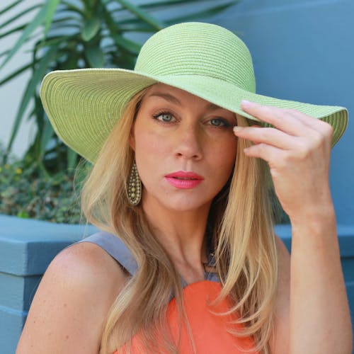 A Woman Wearing a Green Hat and Dangling Earrings