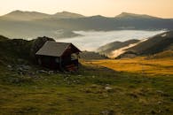 这是一座坐落在薄雾笼罩的乡村景观中的孤独小屋，拥有优美的山景，尤其在日落时分