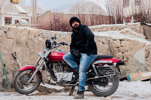 在白雪皑皑的印度户外，一名男子坐在红色摩托车上