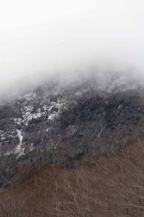 Free A beautiful mist-covered mountain with snow highlights the serene winter landscape. Stock Photo